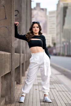 Confident young woman poses stylishly in a contemporary urban setting.