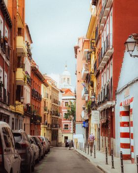 Explore a picturesque narrow street in Madrid, showcasing vibrant architecture and urban charm.