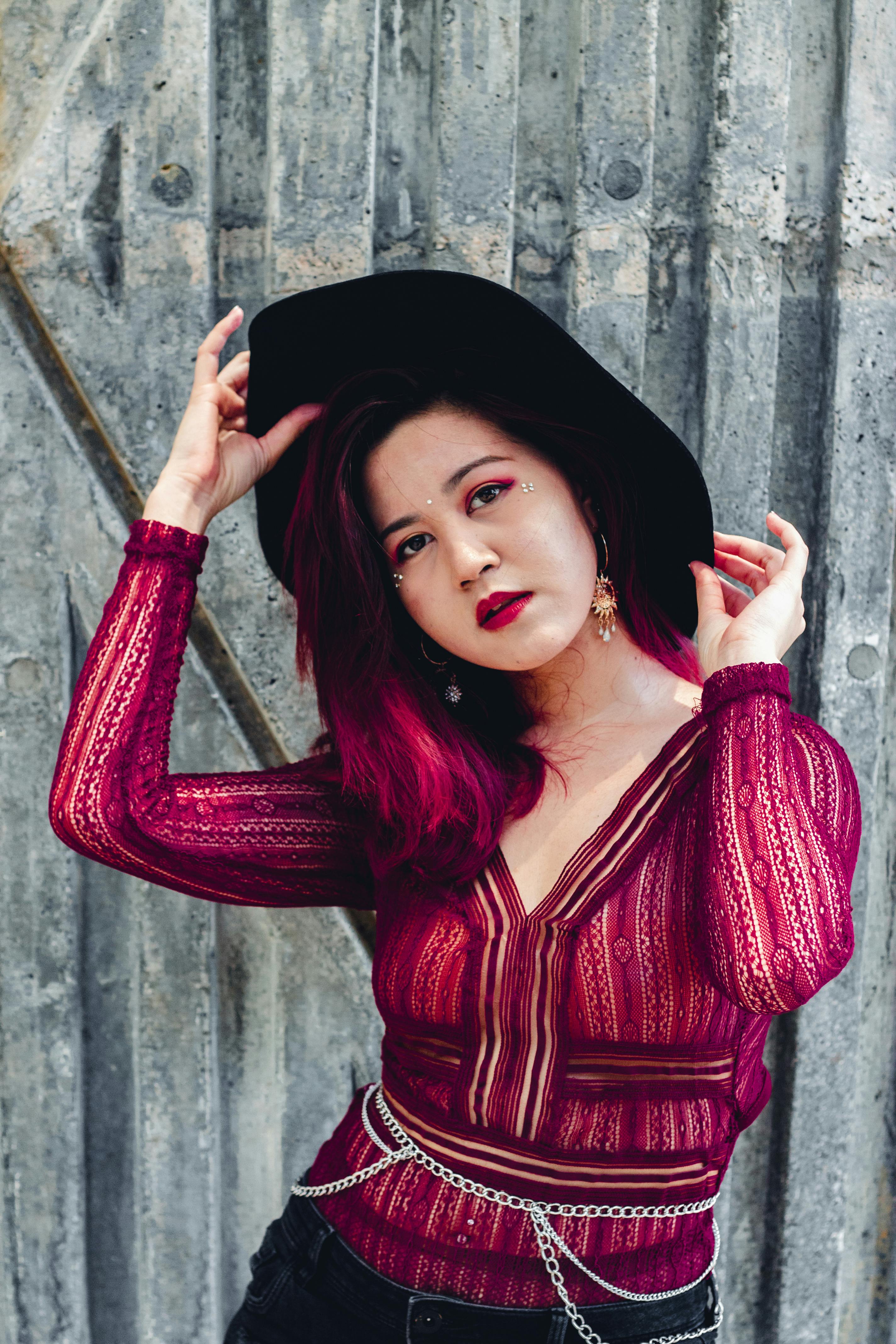 一位穿着蕾丝上衣、戴着帽子的时尚女性在户外纹理背景前摆姿势