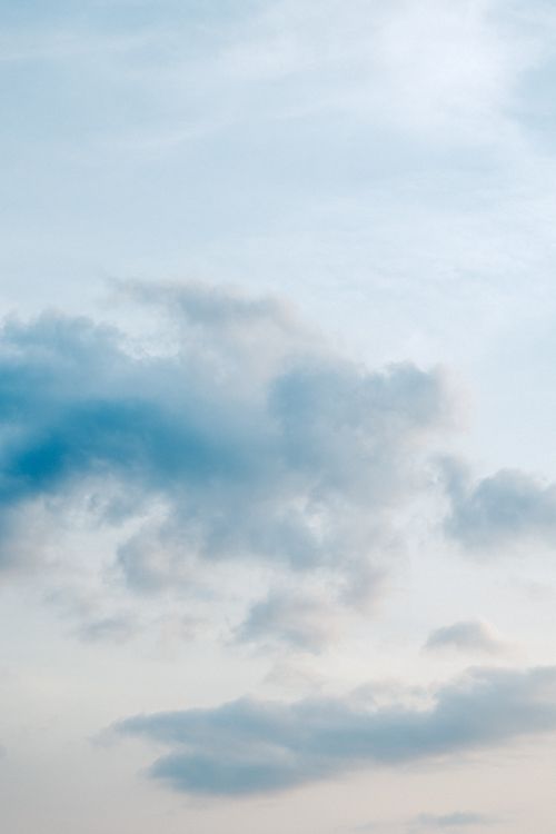 Free A tranquil view of clouds against a blue sky during sunset, capturing nature's peaceful beauty. Stock Photo