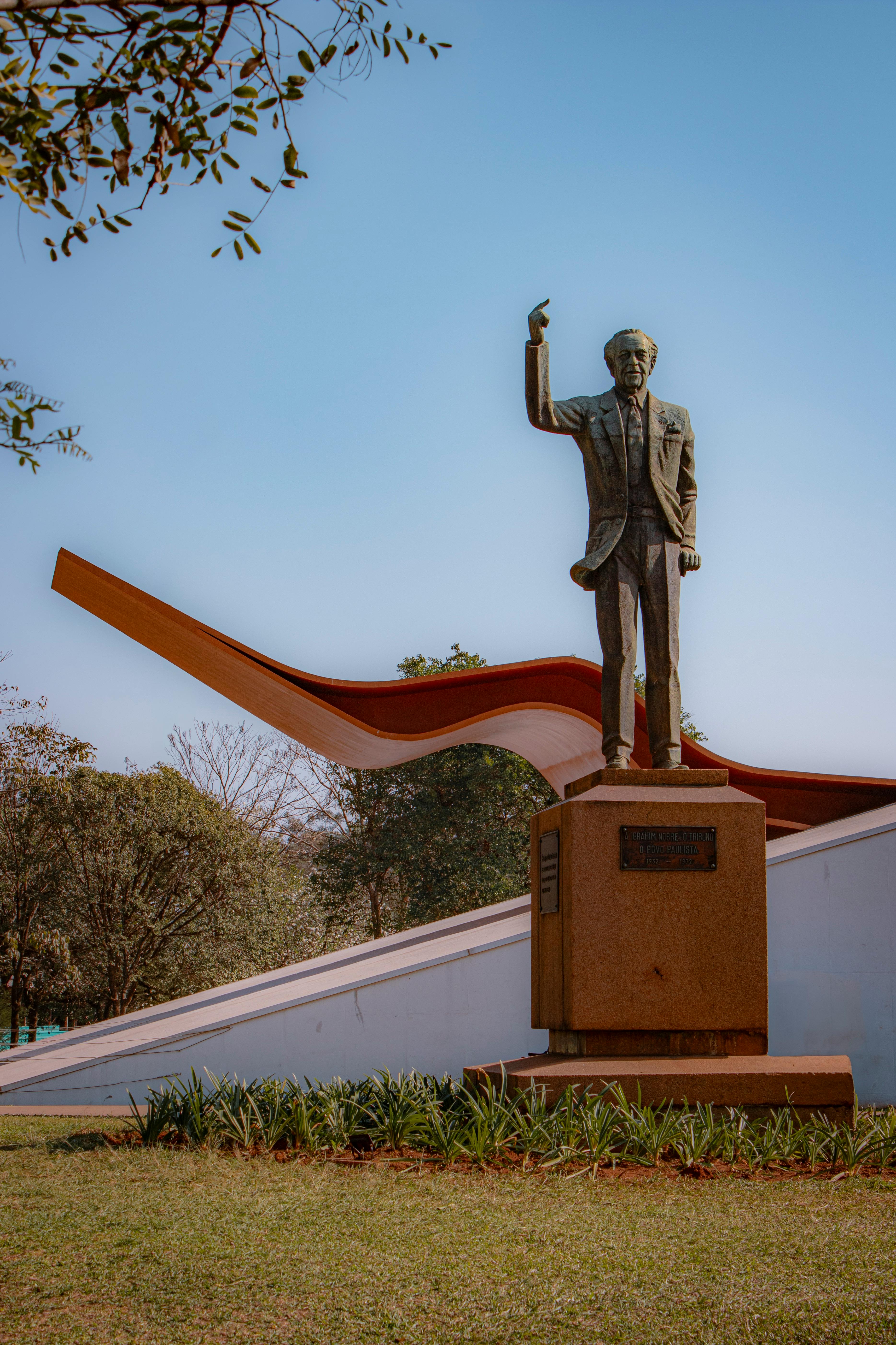 Bronze statue of a man with modern architecture in Ibirapuera Park, São Paulo, Brazil.