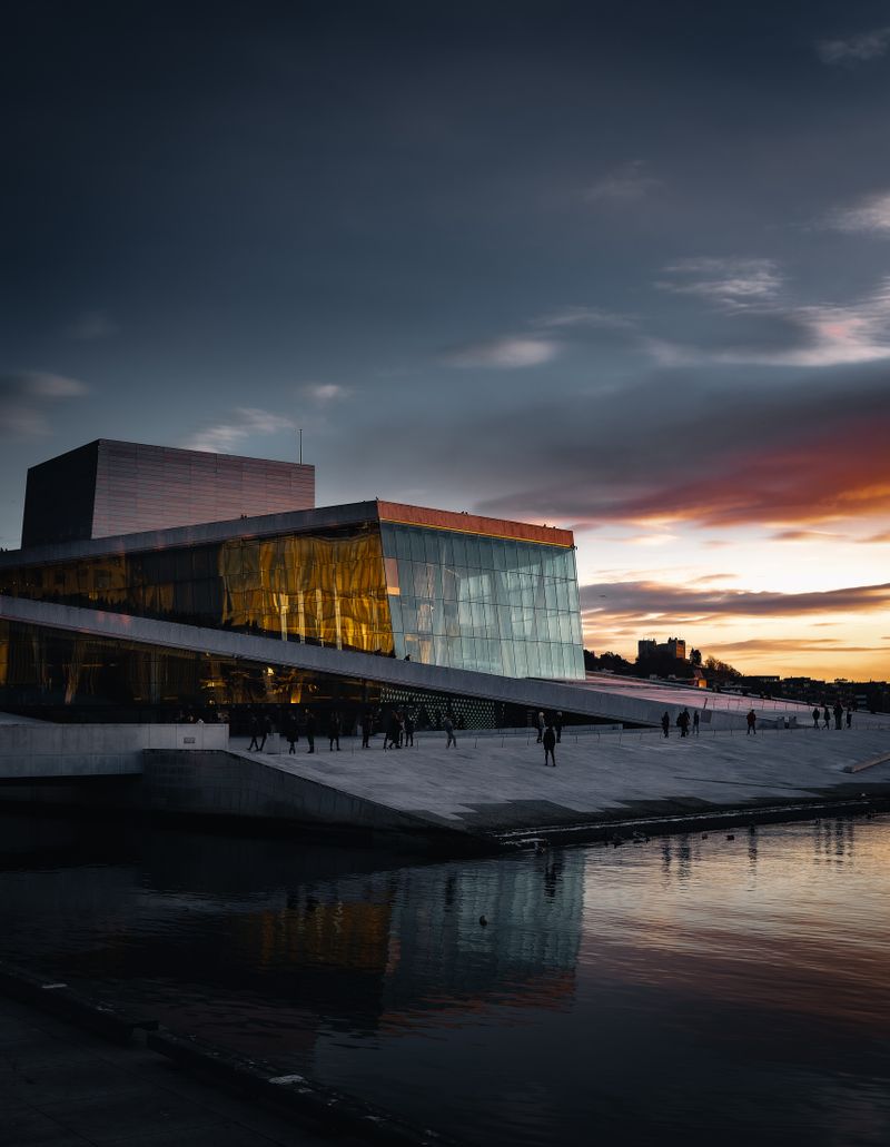 Stunning view of Oslo Opera House with sunset reflecting on the water.