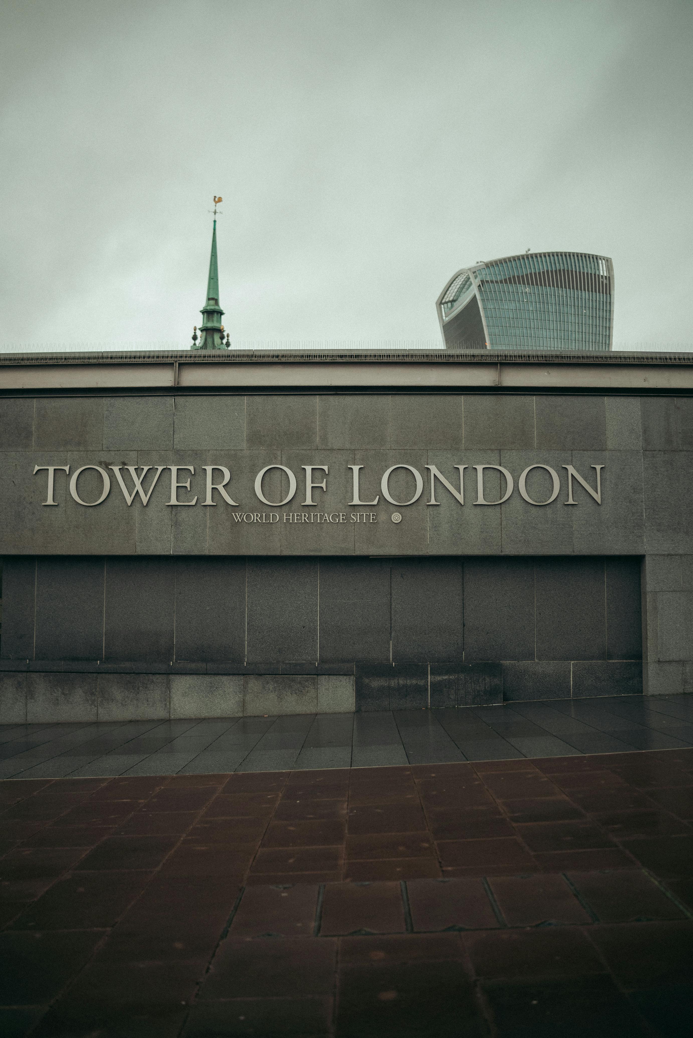 View of the Tower of London entrance with city skyline in the background, featuring modern architecture.