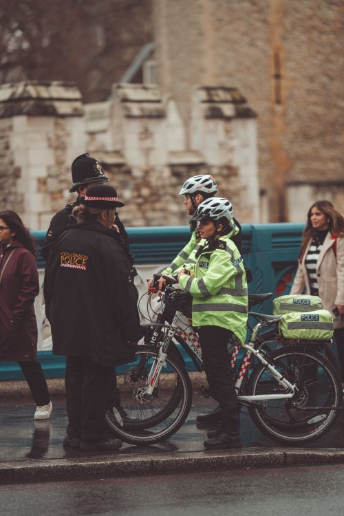 Free Police officers on bikes patrol a city street, engaging with pedestrians. Stock Photo