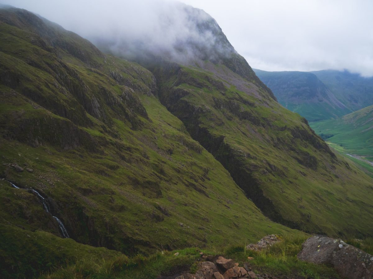 Low cloud clinging to steep green crags above a Lakeland valley.