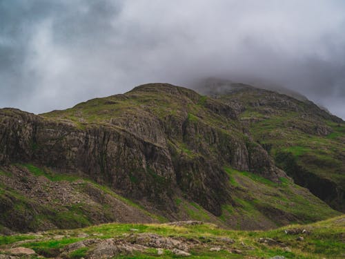 Free A scenic mountain landscape with rocky cliffs and misty fog under cloudy skies, perfect for nature lovers. Stock Photo