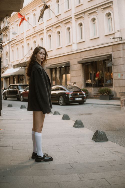 Free Woman in stylish outfit posing on city street with urban architecture in the background. Stock Photo