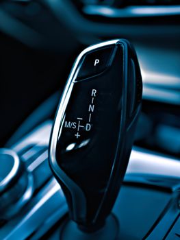 Close-up image of a modern automatic gear shift lever in a luxury car, displaying gear options.