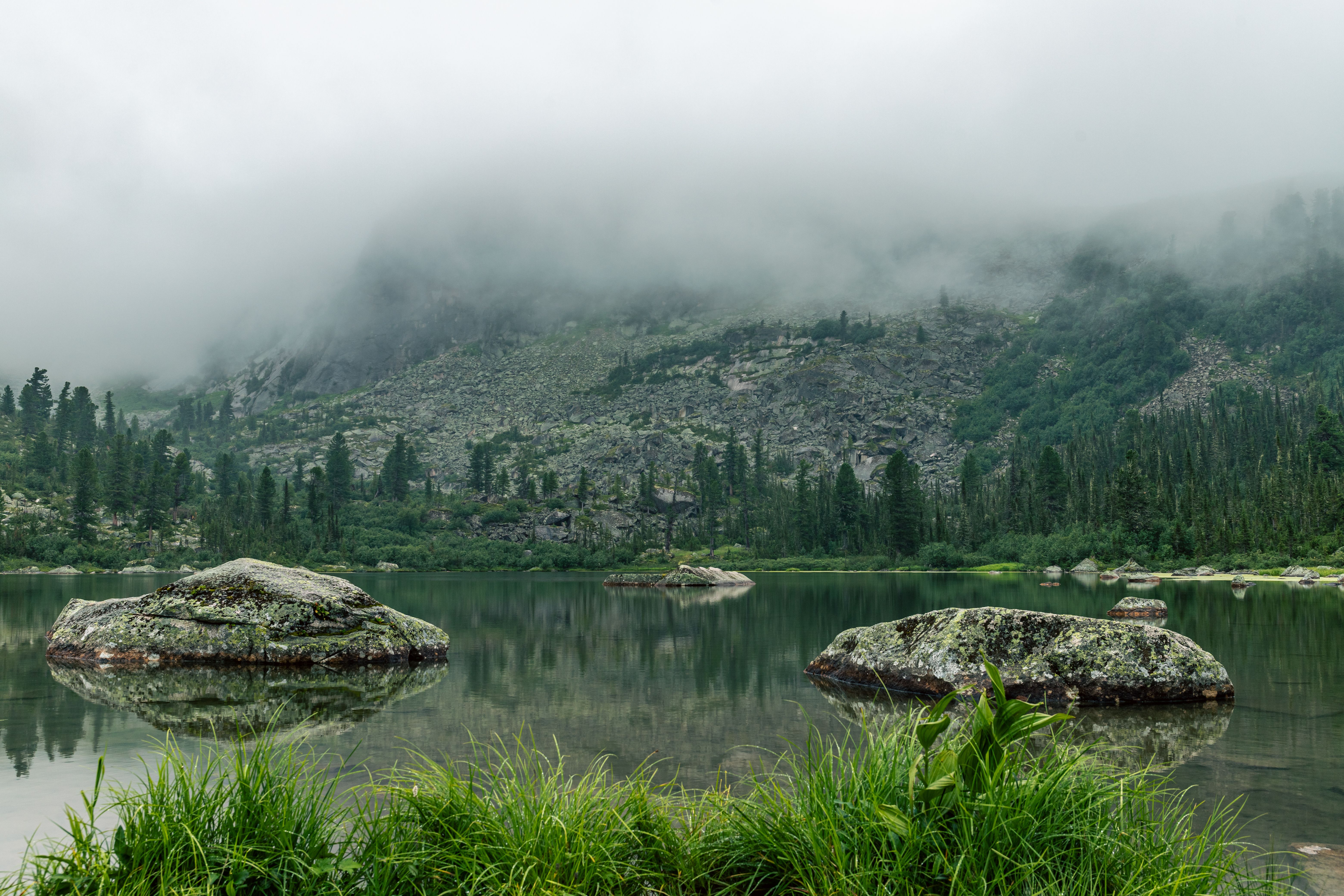 A lake surrounded by rocks and trees in the mountains · Free Stock Photo