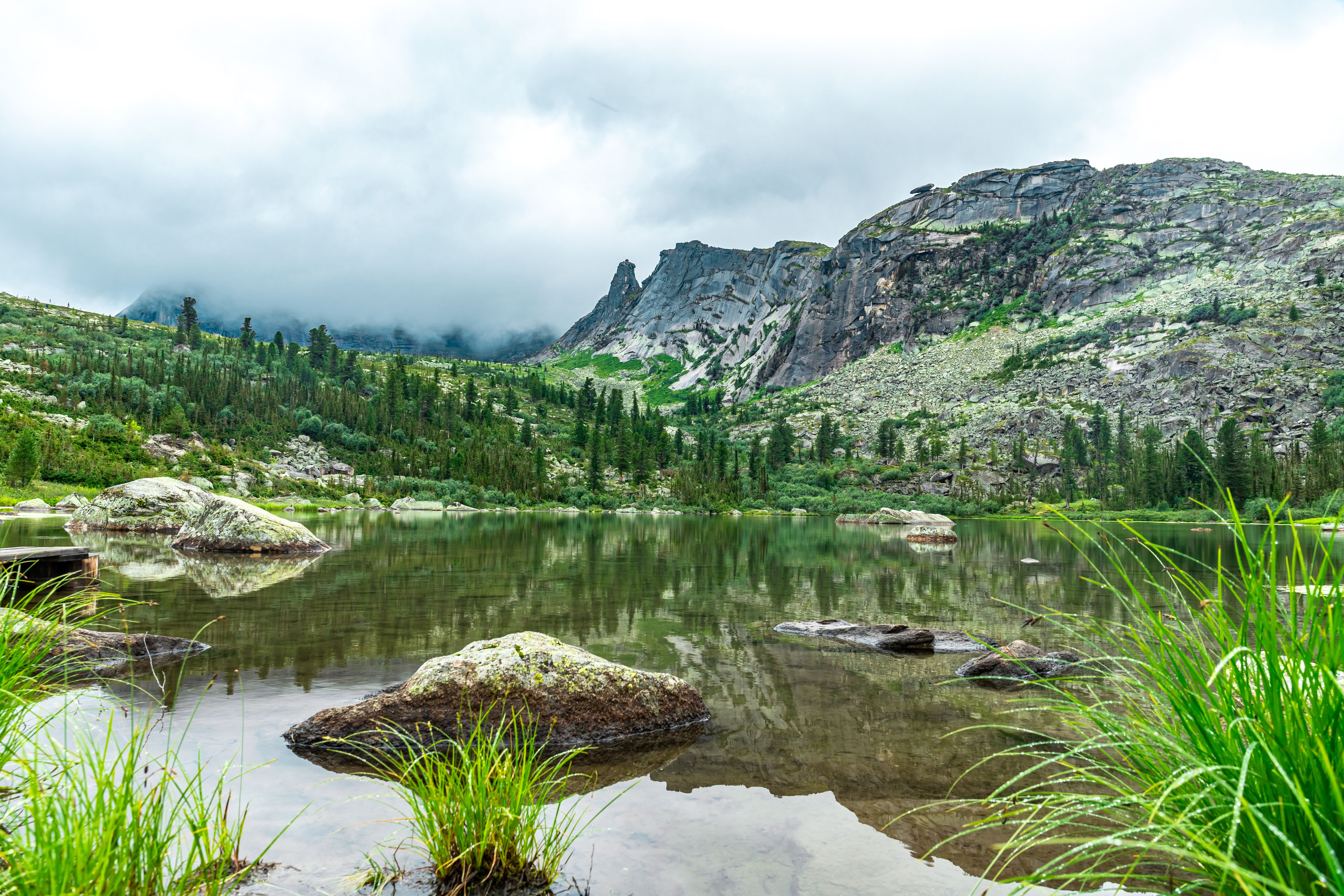A mountain lake surrounded by grass and rocks · Free Stock Photo
