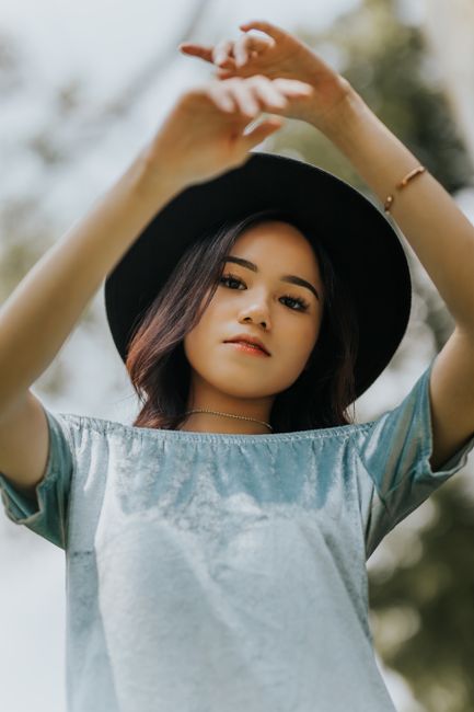 Fashionable woman in a sun hat posing outside on a sunny day.