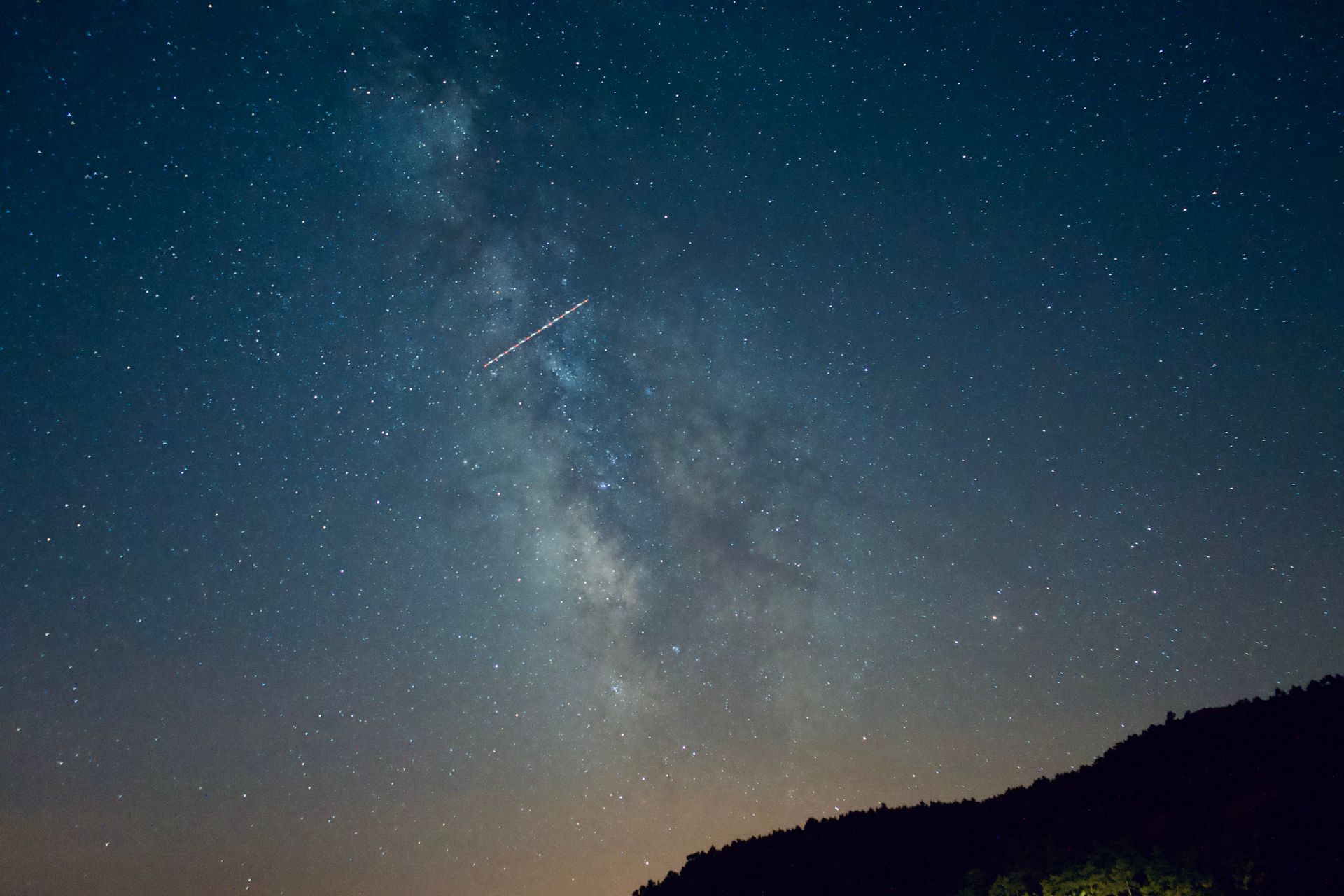 A shooting star is seen in the sky above a mountain