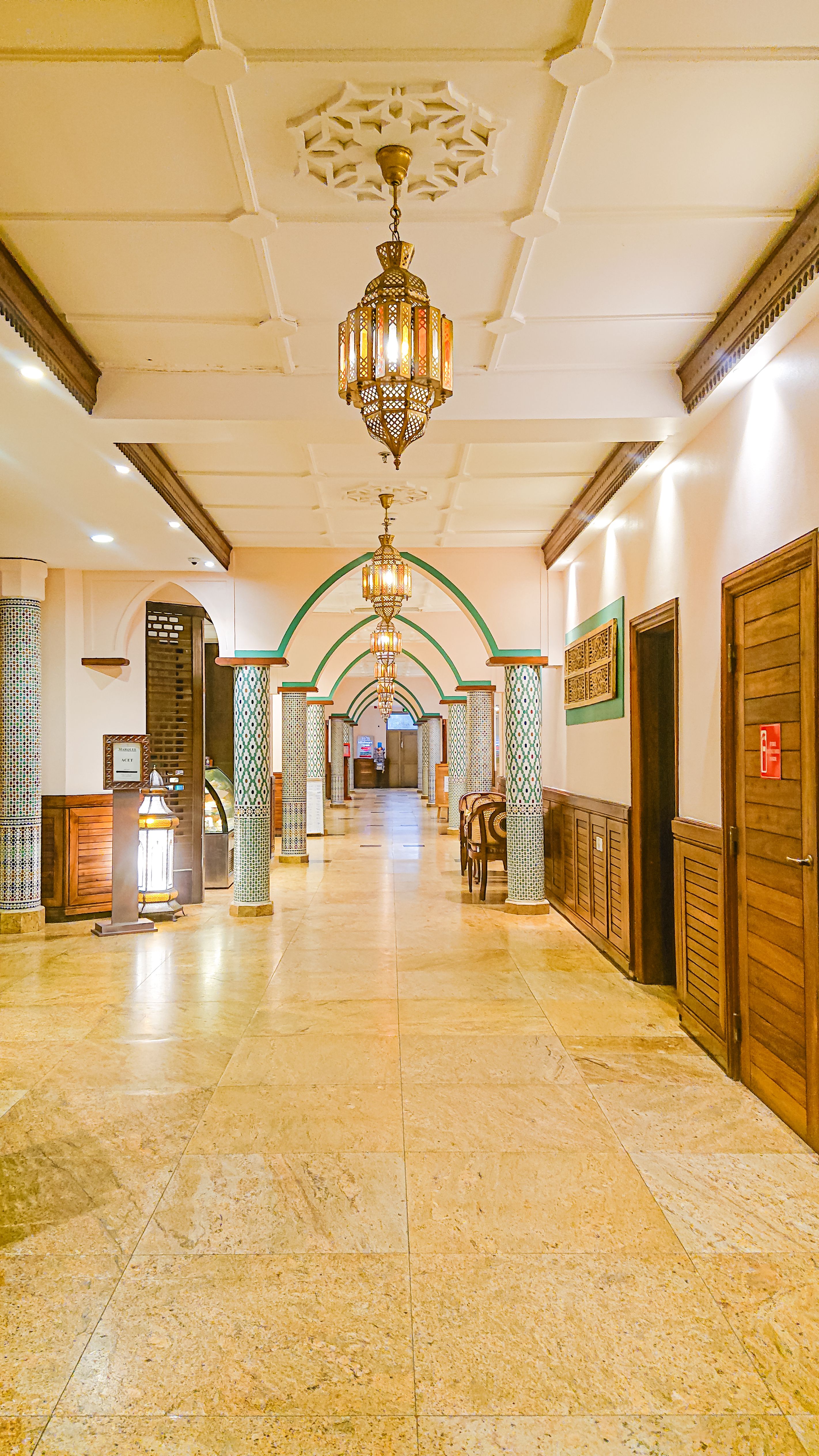 Luxurious Moroccan-inspired hallway in a hotel with intricate ceiling, lanterns, and arched columns in Dar es Salaam.