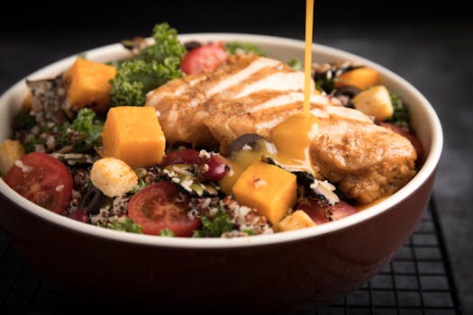 A colorful chicken salad with honey dressing, featuring fresh vegetables and grains.