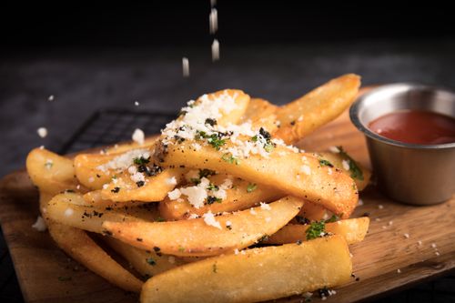Free Delicious golden french fries topped with grated cheese and herbs, served with ketchup. Stock Photo