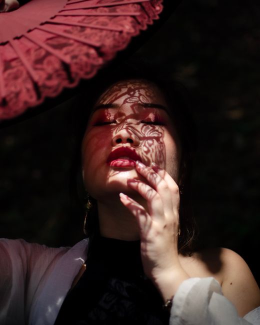 Artistically patterned shadows cast on a woman's face by a fan, creating a serene and elegant portrait.