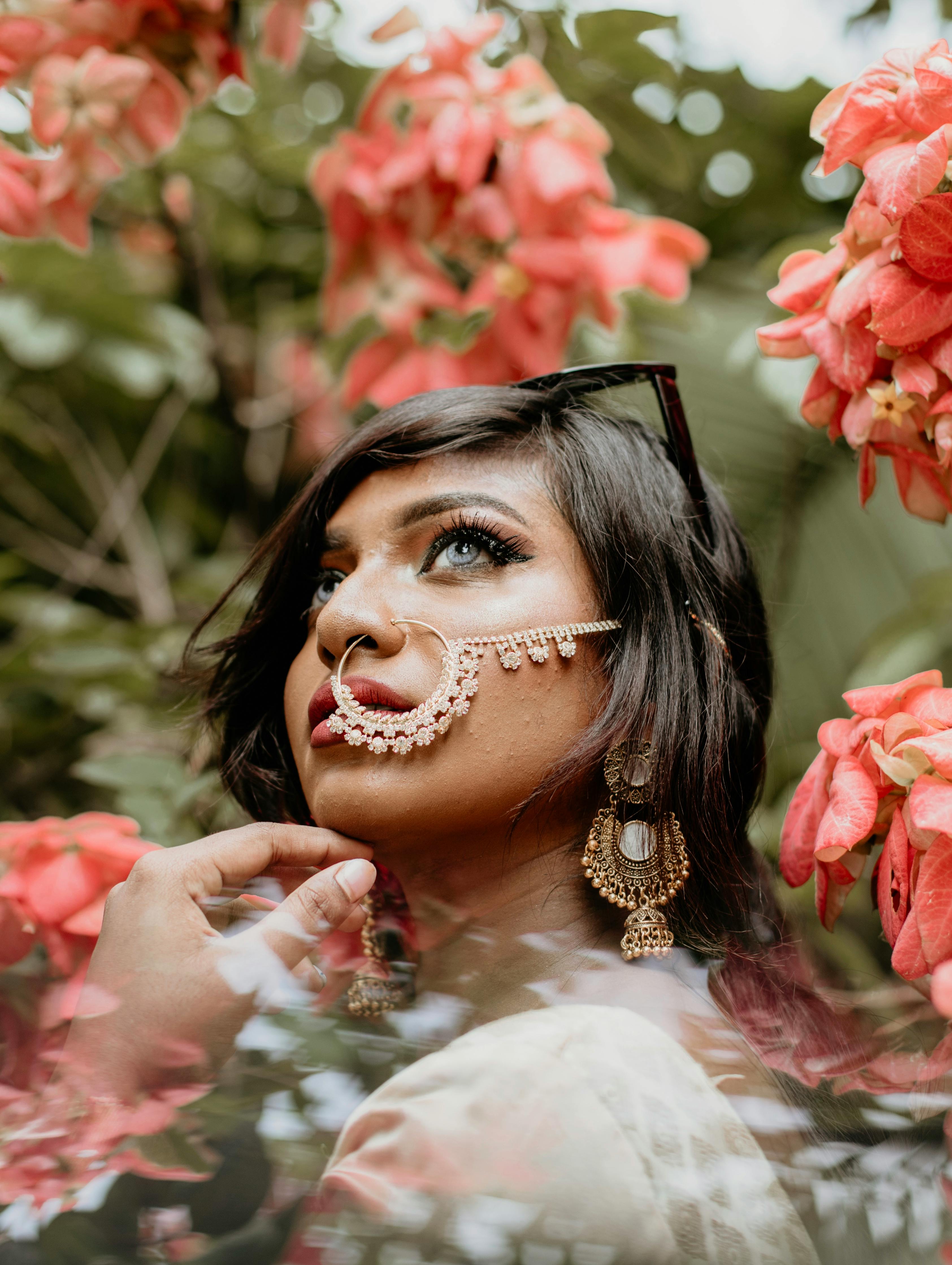 close up photography of woman standing beside pink petaled flowers