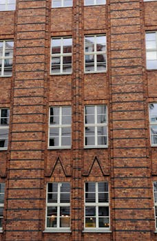 Close-up view of a brown brick building with multiple windows in an urban setting.