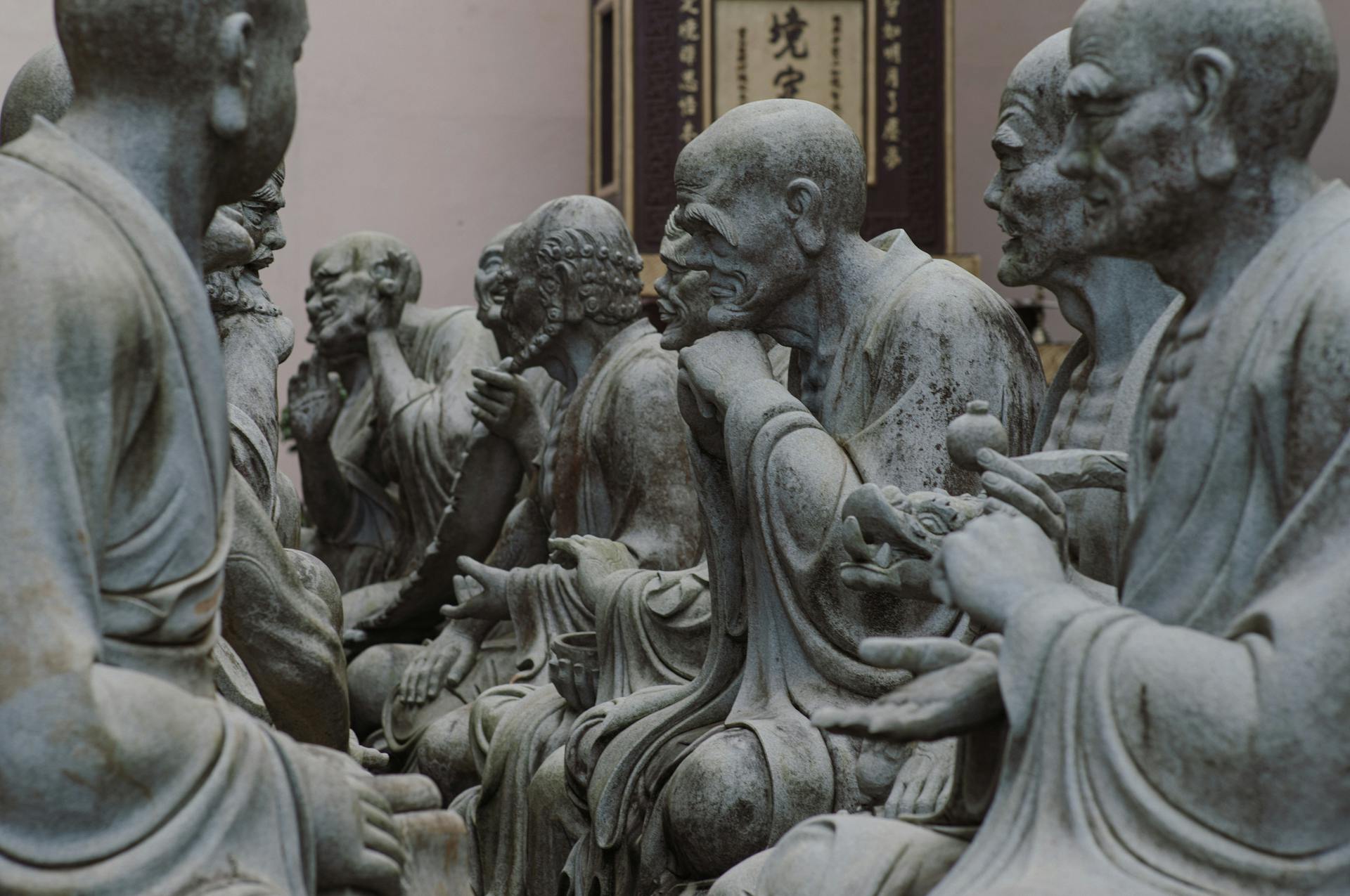 A group of statues of buddhist monks sitting in a room