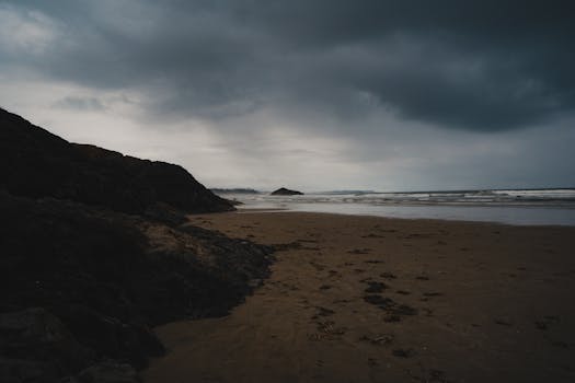 A dramatic beach scene with dark clouds and waves crashing on the shore, evoking a sense of solitude.
