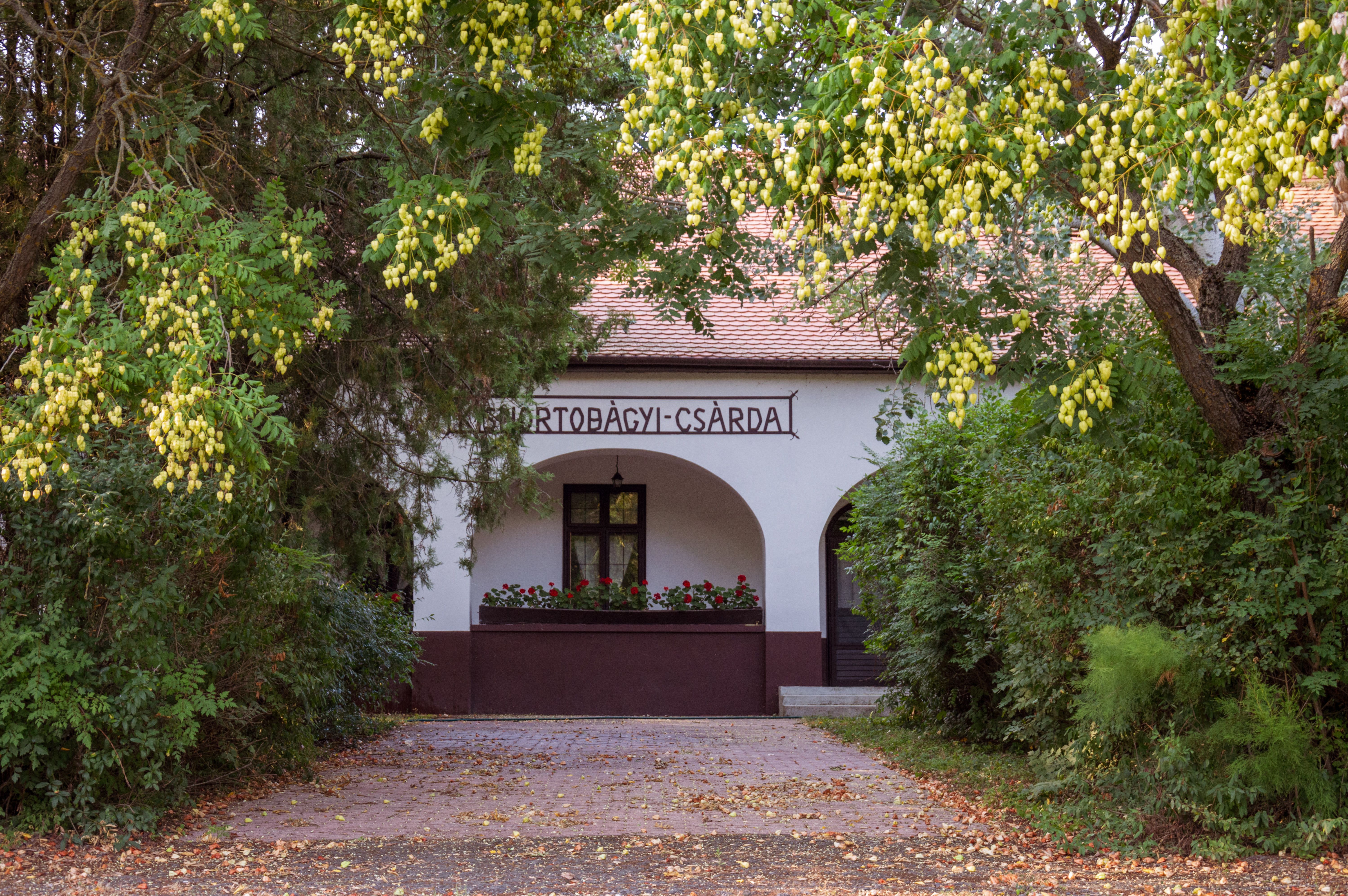 Charming country inn surrounded by rich foliage and vibrant flowers in a serene setting.