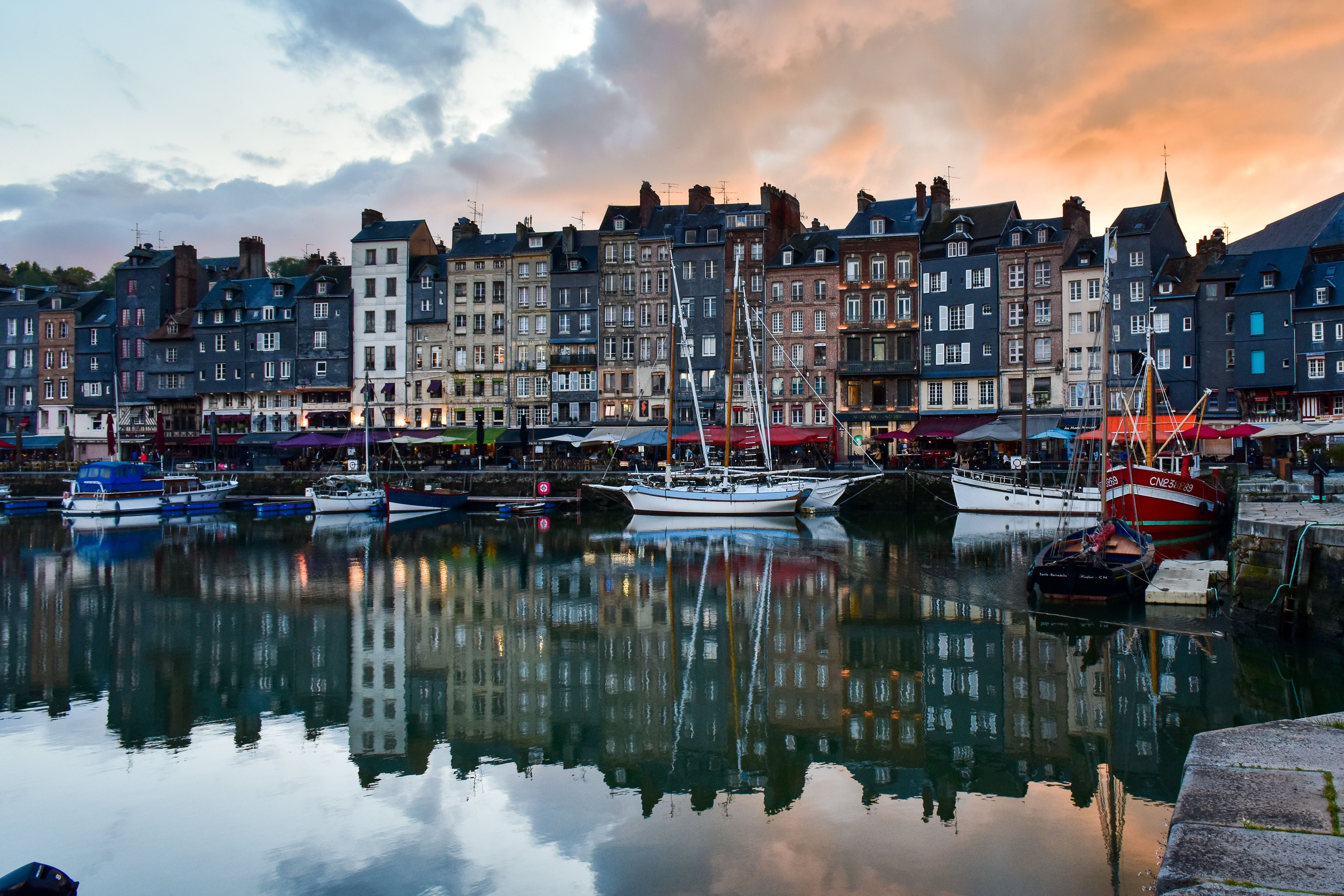 Honfleur harbor colorful buildings with slate-covered façades reflecting in the Vieux Bassin at golden hour