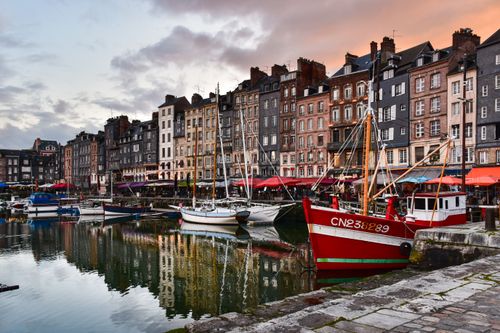Free Scenic view of Honfleur harbor with colorful buildings and boats at sunset. Stock Photo