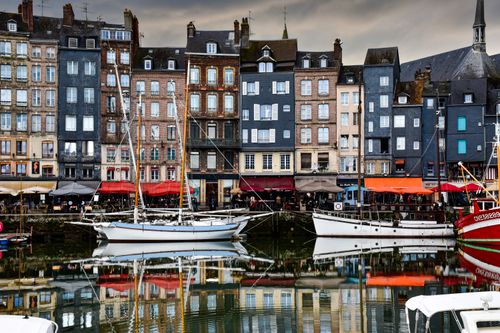 Free Colorful buildings reflect in the peaceful waters of Honfleur's historic harbor. Stock Photo