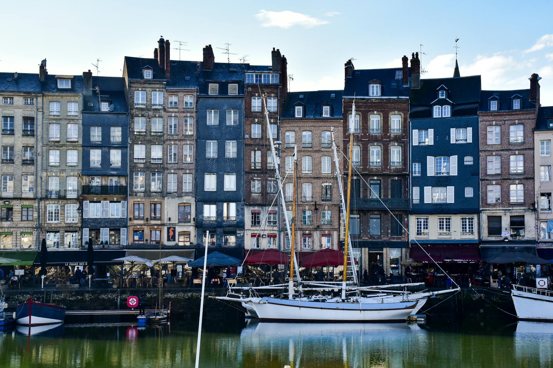 Iconic waterfront buildings and boats in Honfleur, Normandy, showcasing French architectural charm.