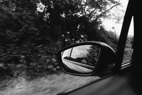 Free A scenic drive captured in the side mirror, revealing nature in black and white reflection. Stock Photo