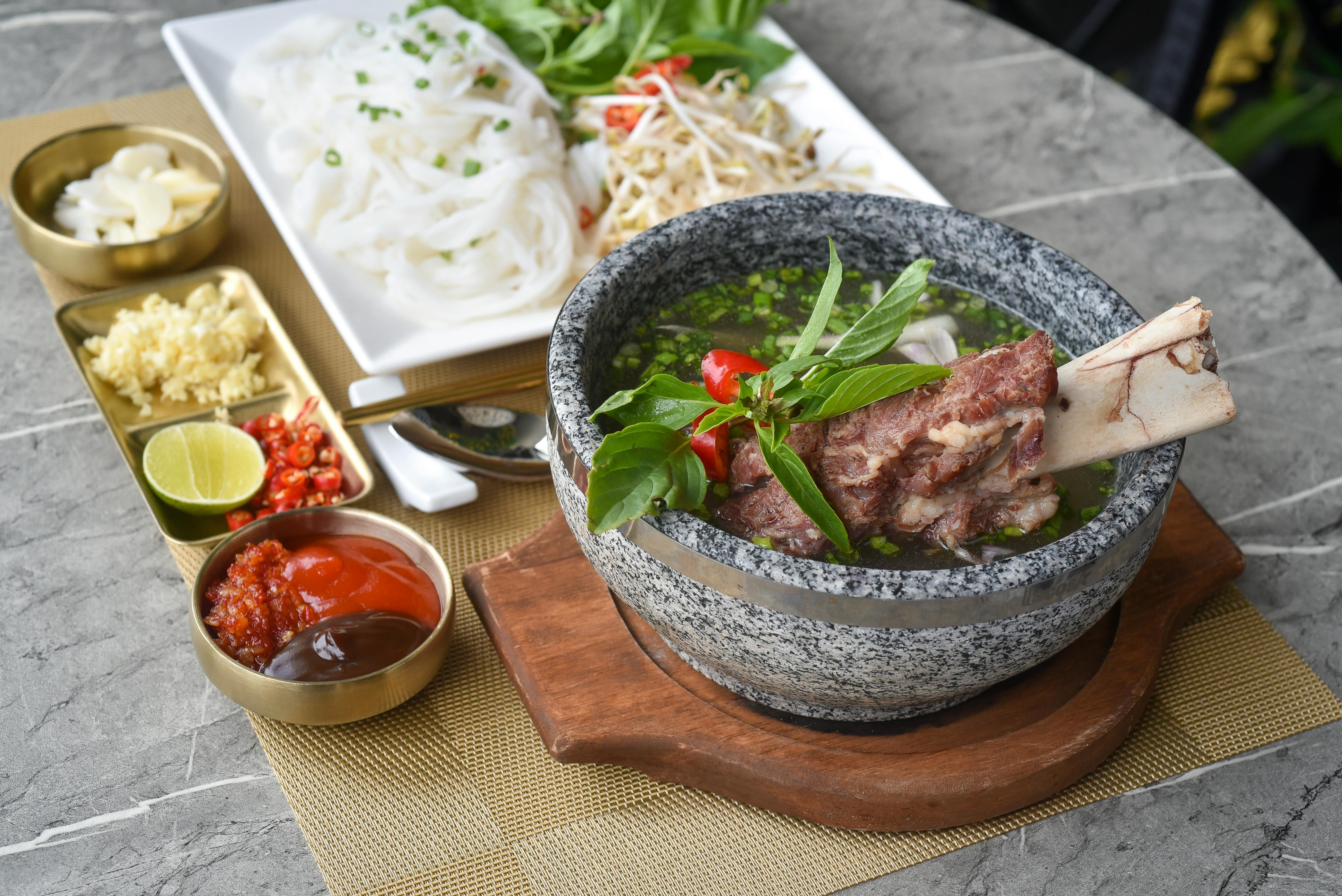 A bowl of milky beef-bone gomtang at Hadongkwan Apgujeong, with white tablecloth and wooden booth