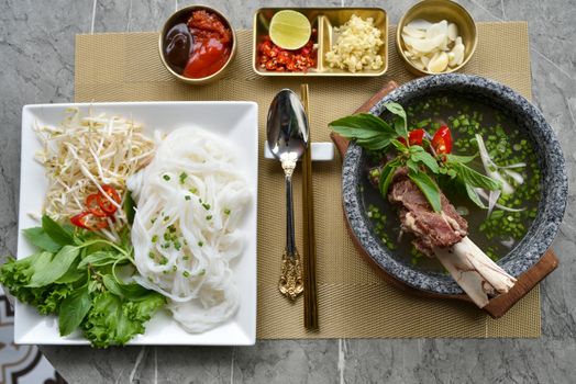 A vibrant layout of Vietnamese pho with fresh herbs, noodles, and condiments.