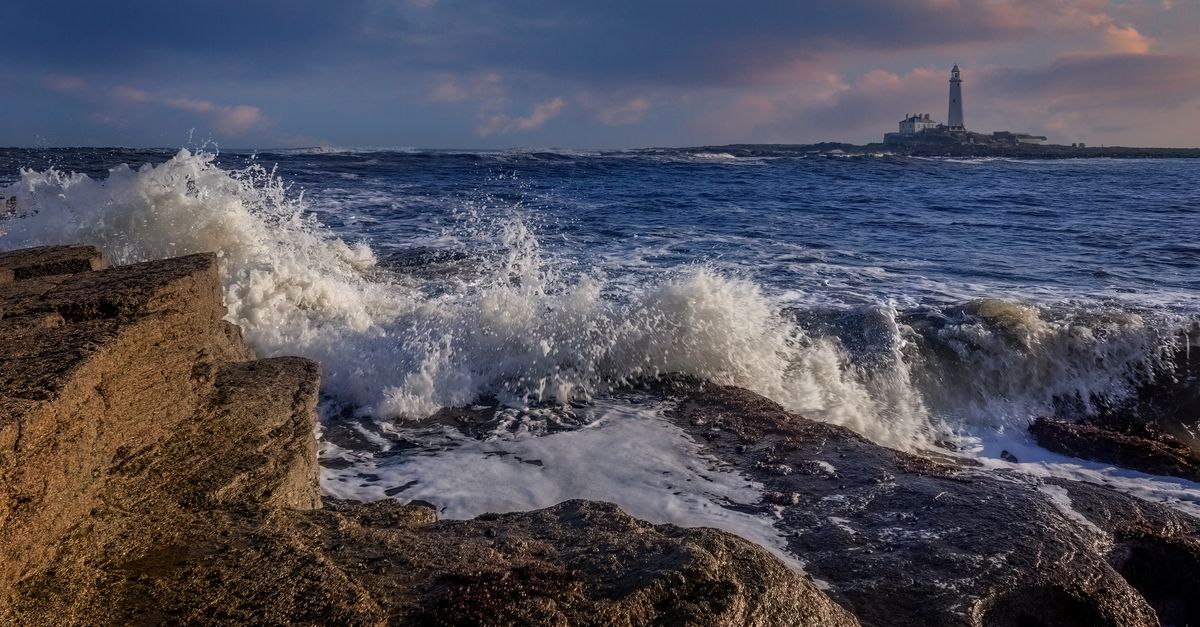 Lighthouse And Rocks A lighthouse and rocks in the ocean at sunset · Free Stock Photo