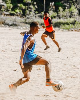 Two athletes playing soccer on a sunny beach, highlighting fitness and fun.