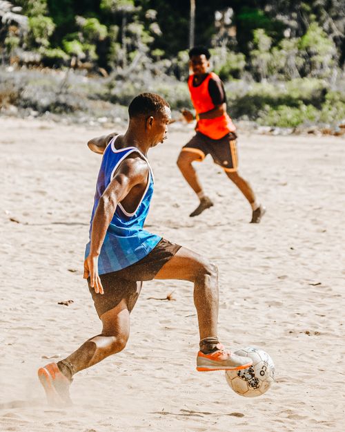 Free Two athletes playing soccer on a sunny beach, highlighting fitness and fun. Stock Photo