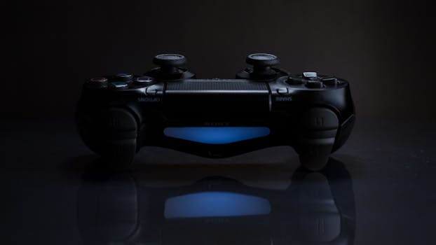 Close-up of a gaming controller with a soft blue light in a dark setting.