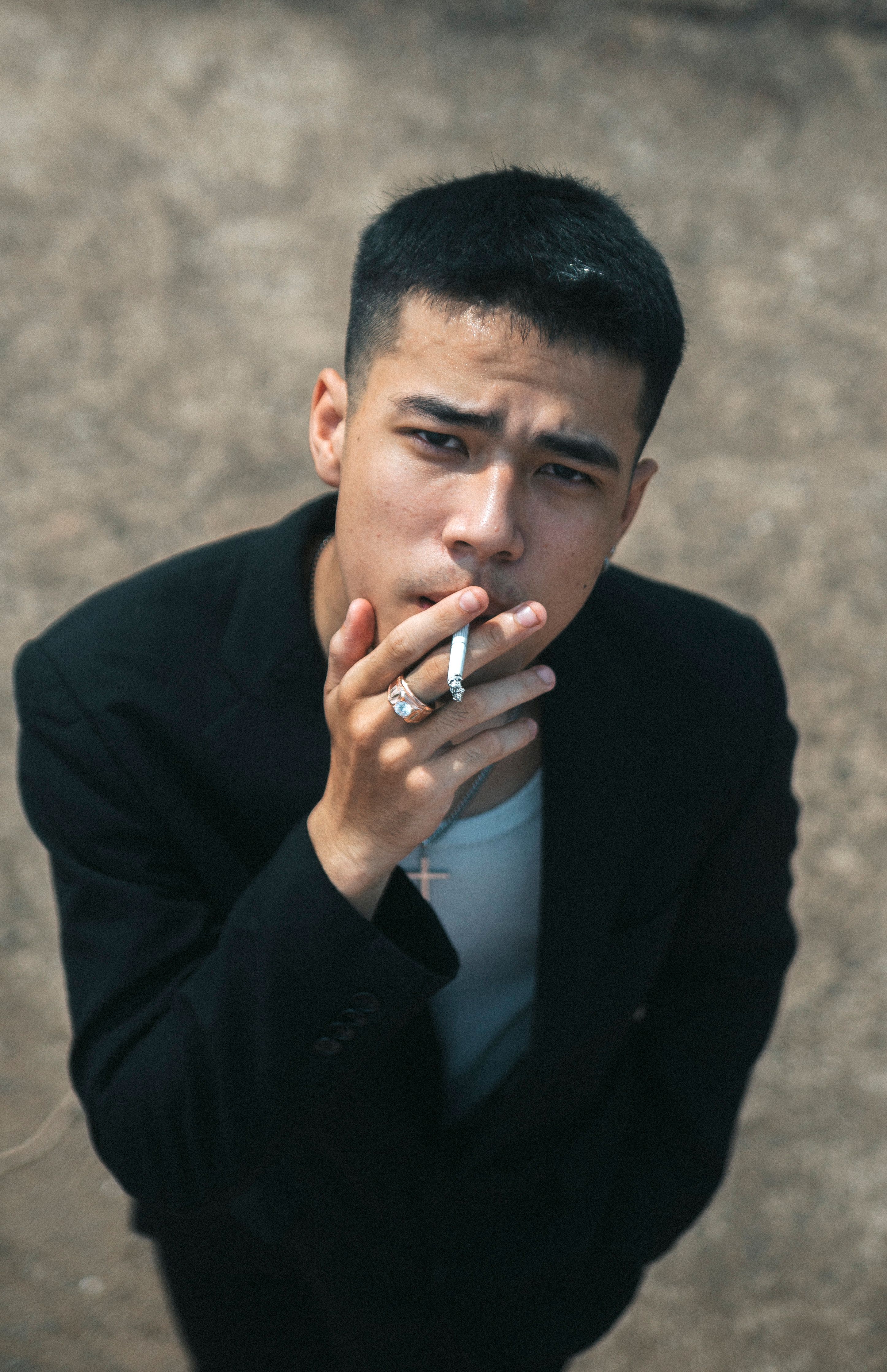 Portrait of a thoughtful young man smoking outdoors, exuding a serious mood.