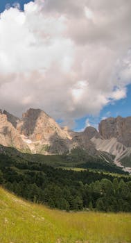 Beautiful summer landscape of the Dolomites in Santa Cristina Valgardena, Italy, with clouds and lush greenery.