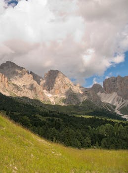 Breathtaking landscape of the Dolomites with lush greenery and dramatic clouds during summer.
