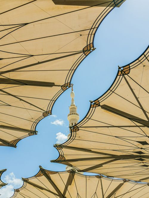 Free Architectural umbrellas with a tower spire peeking through against a blue sky. Stock Photo