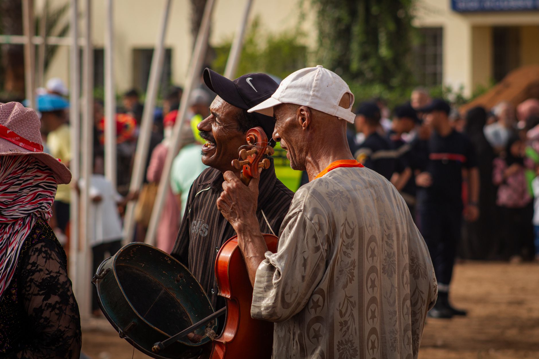Two musicians performing outdoors in Sidi Moussa El Mejdoub, Morocco, with vibrant atmosphere.