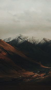 Scenic view of a snow-capped mountain range at twilight with a serene valley.