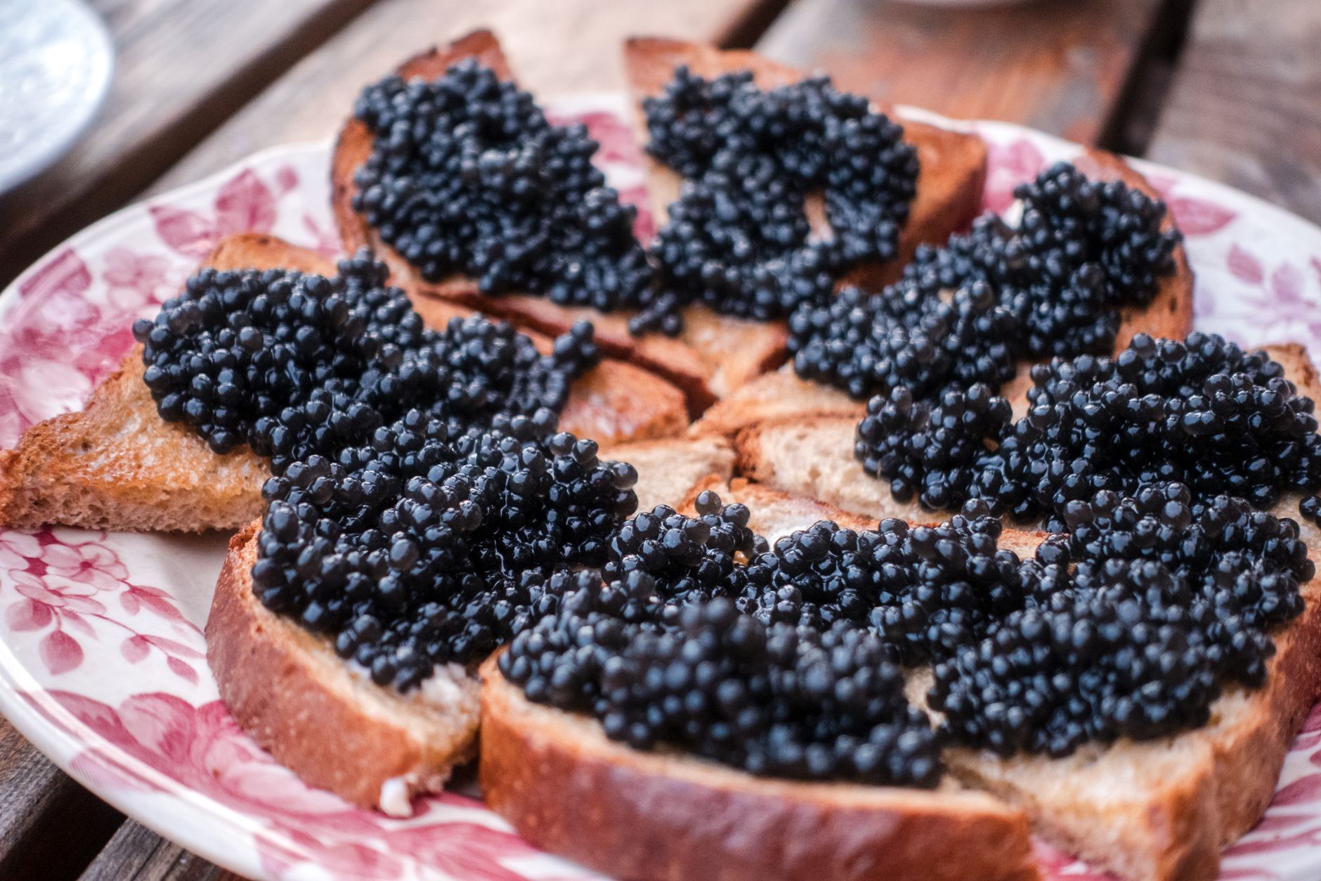 Close-up of caviar on a mother-of-pearl spoon held over plate