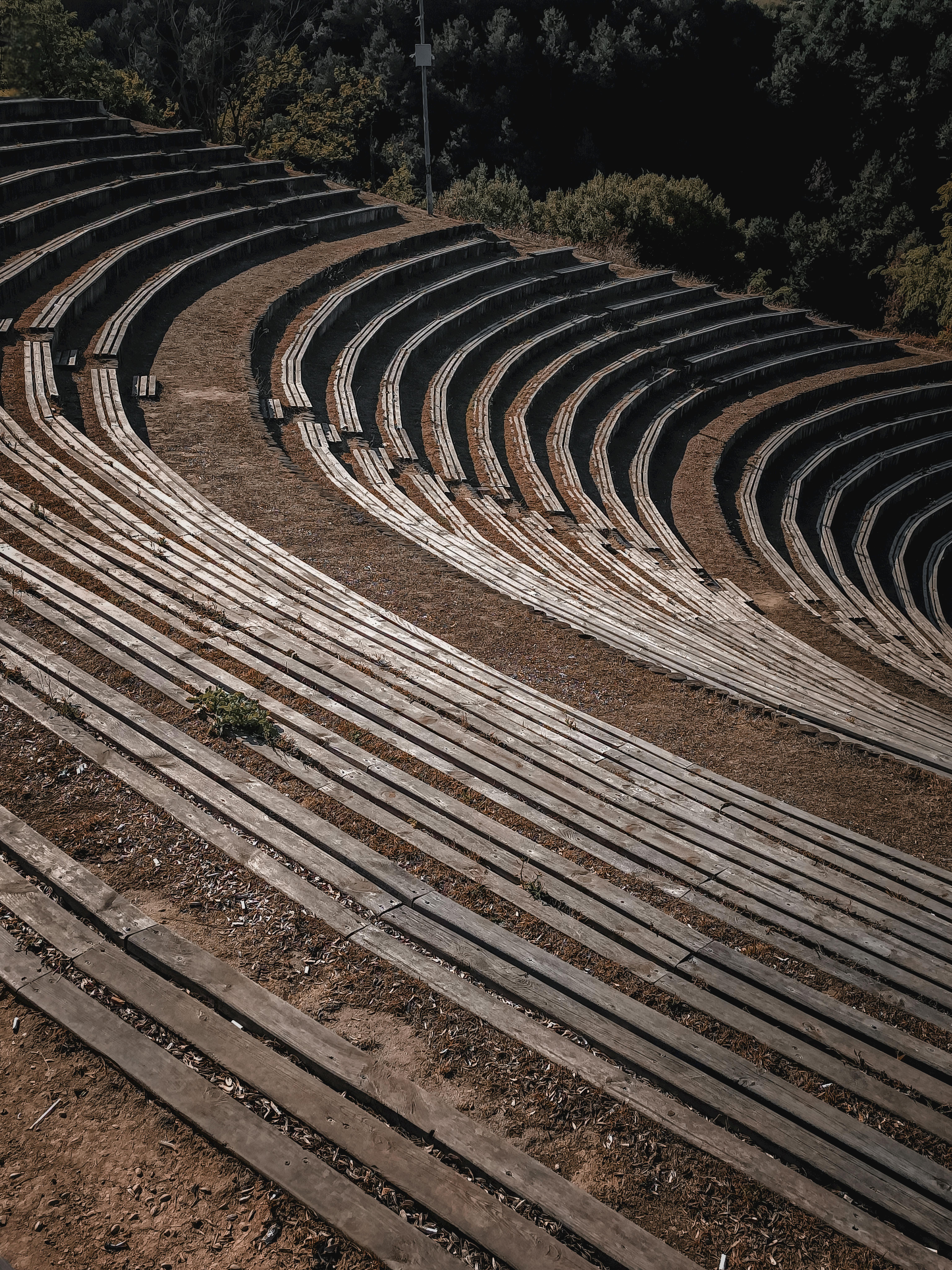 Free An empty curved wooden amphitheater set amidst nature, showcasing architectural elegance and tranquility. Stock Photo
