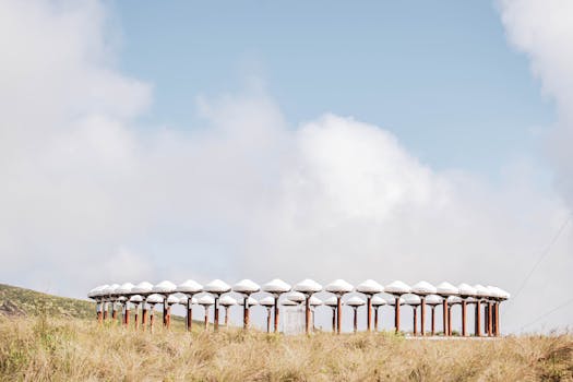A distinctive circular structure stands in a grassy field under a clear blue sky.