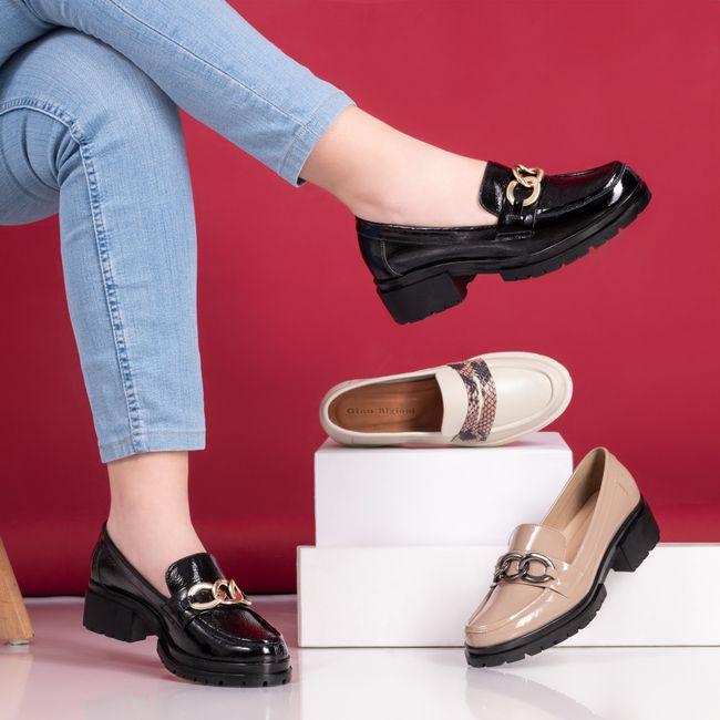 Fotomural Mocasines elegantes para mujer con cadenas decorativas sobre un fondo rojo. Perfecto para una colección de calzado de moda estilosa.