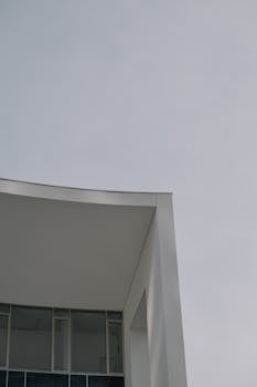A modern minimalist building with steel and glass elements under a clear sky.