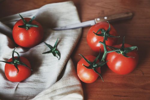 Free Vibrant cherry tomatoes on a rustic cloth with a knife, ideal for healthy cooking concepts. Stock Photo