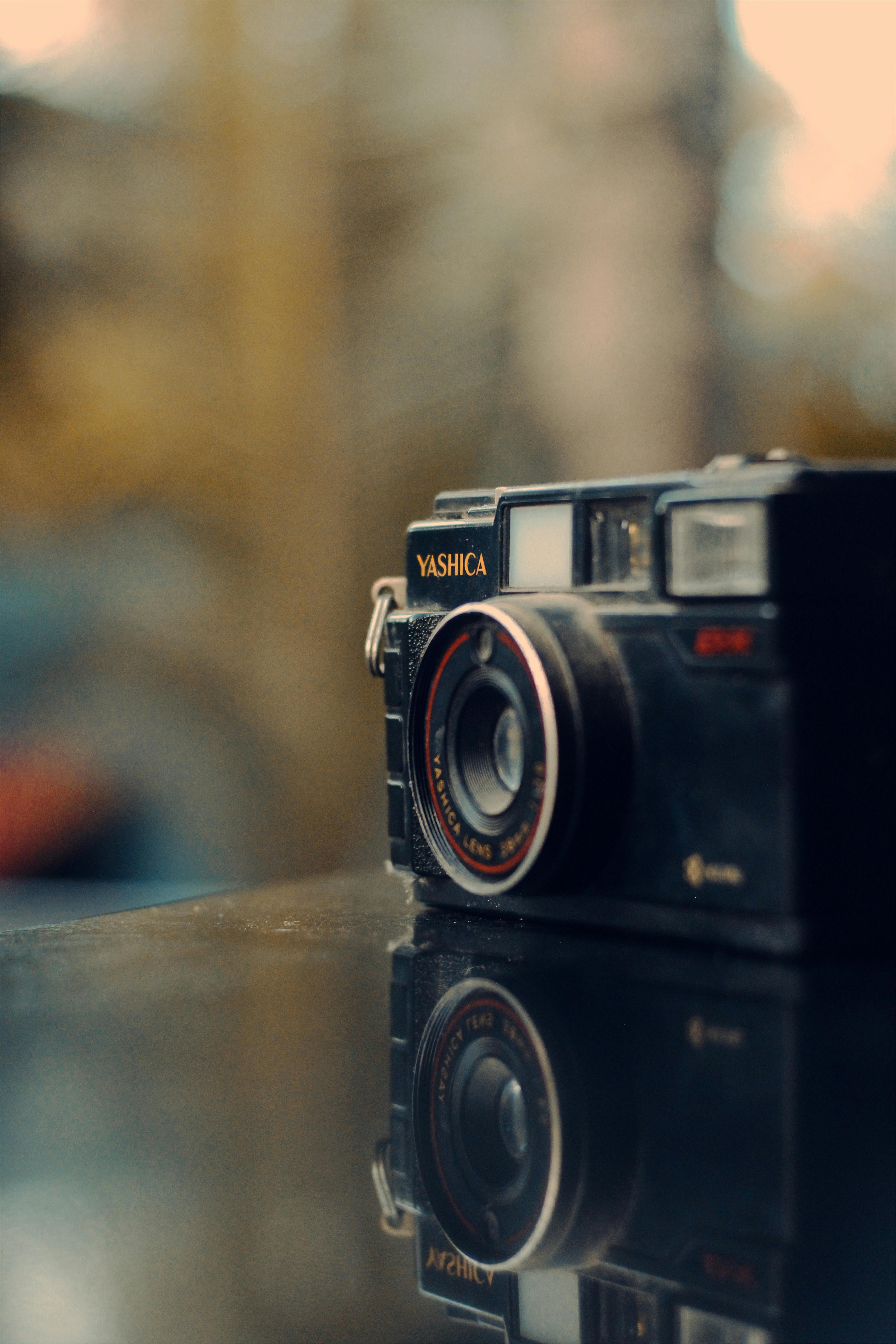 Zbliżenie klasycznego aparatu Yashica na lustrzanej powierzchni, wywołujące nostalgię.