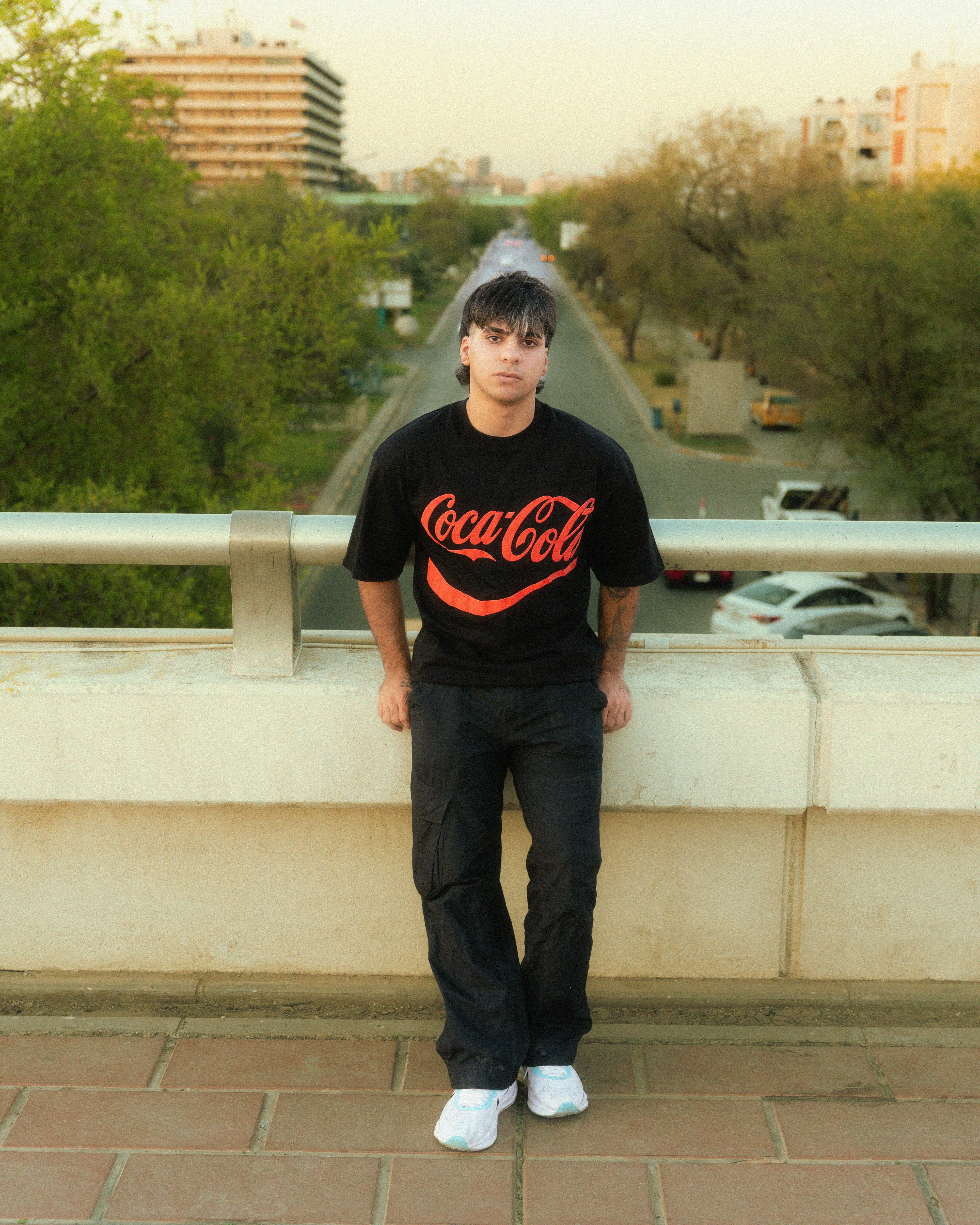 a man standing on a ledge with a coca cola shirt